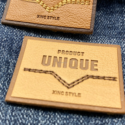 Юқори сифатли махсус ювилиши мумкин бўлган нақшинкор логотип жинси кўйлаги учун ПУ тери ёрлиғи ёрлиғига тикилган